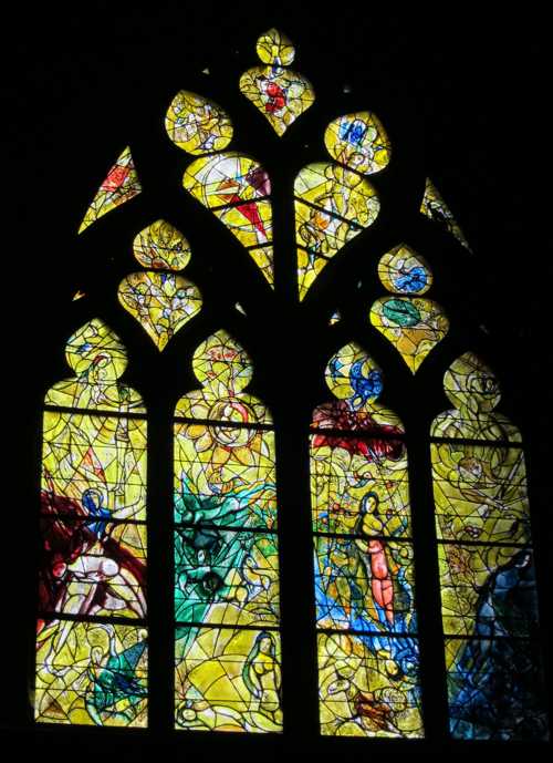 Le vitrail de Marc Chagal dans le transept gauche (1963): de gauche à droite, la création d'Adam et d'Eve, le paradis terrestre, le péché originel et Adam et Eve chassés du paradis.