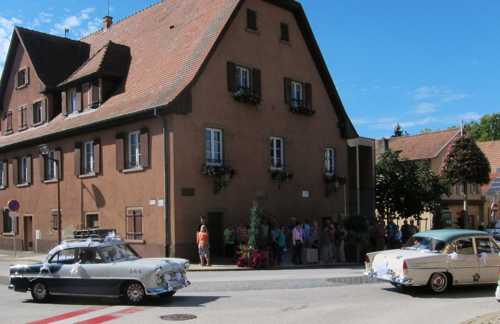 Devant l'ancienne mairie, passage de voitures anciennes, à l'occasion d'un mariage célébré le même jour.
