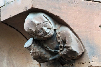 Le buste représente une jeune femme souriante tenant la mesure à vin utilisée à Haguenau et autour du cou, elle porte l'emblème de la ville, la rose quintefeuille.